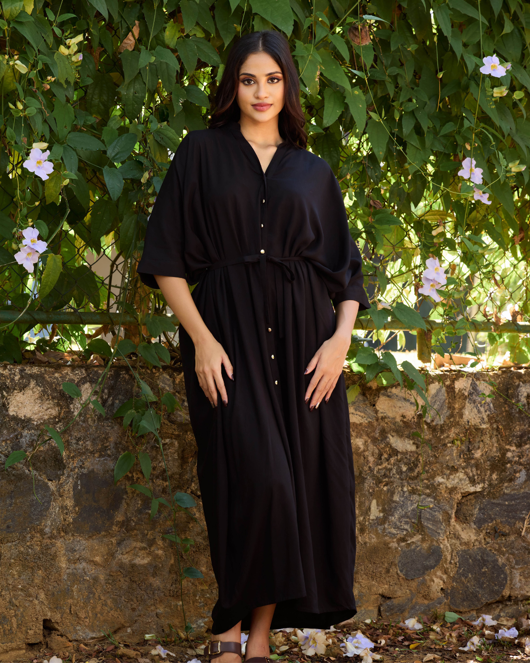 Black relaxed fit maxi dress for women in Sri Lanka with button front and waist tie detail, styled in a natural outdoor setting